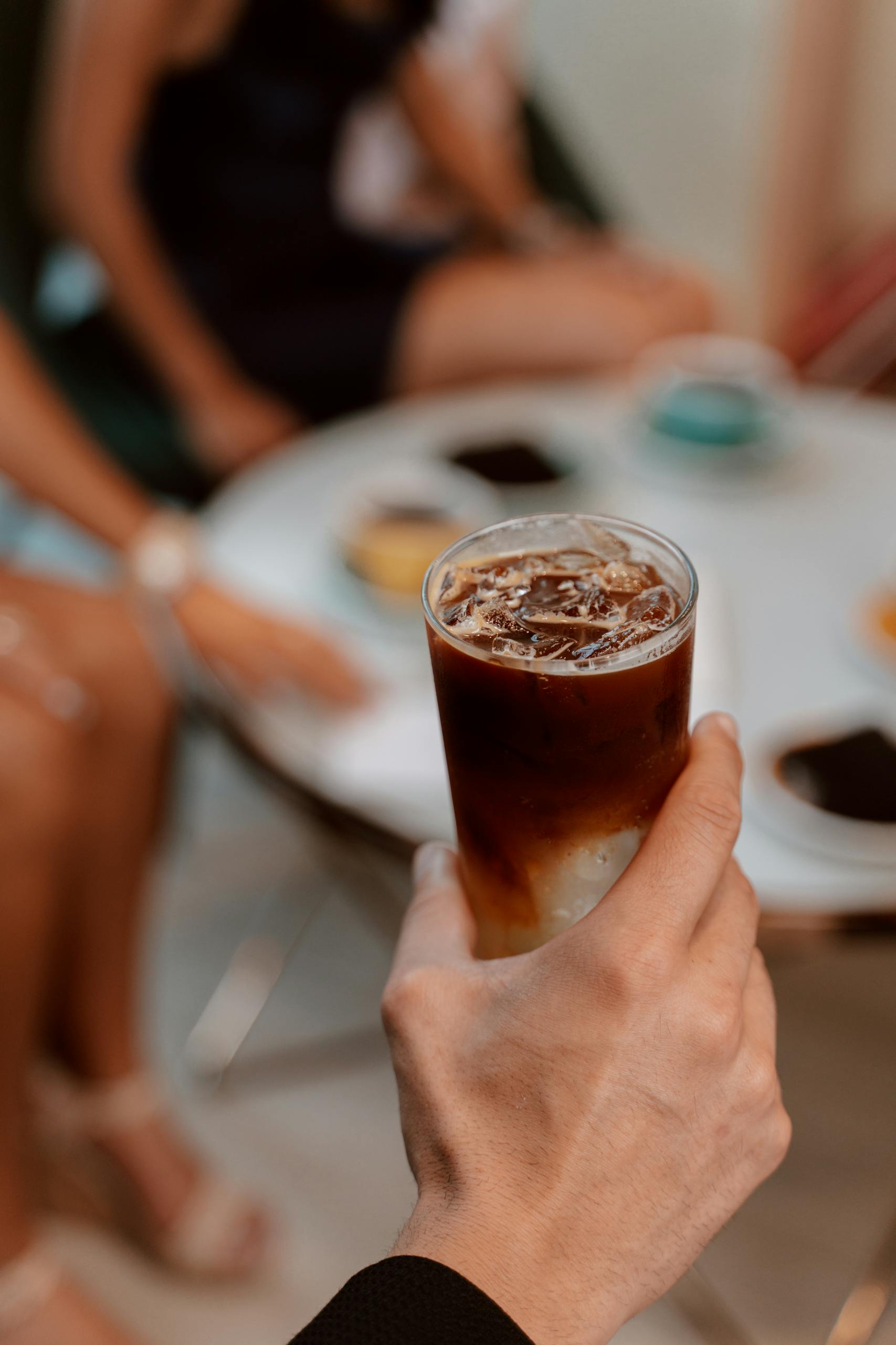 Close-Up Shot of a Person Holding Iced Coffee in a Glass